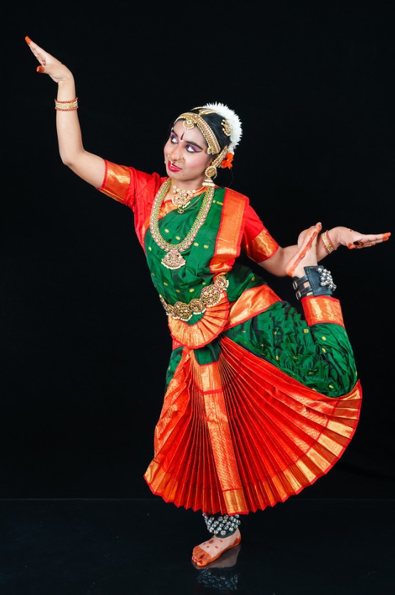 Lasya Voonna performing Bharatanatyam in traditional red and green costume with gold jewellery
