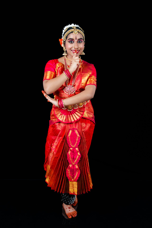 Lasya Voonna performing Bharatanatyam in traditional red and green costume with gold jewellery